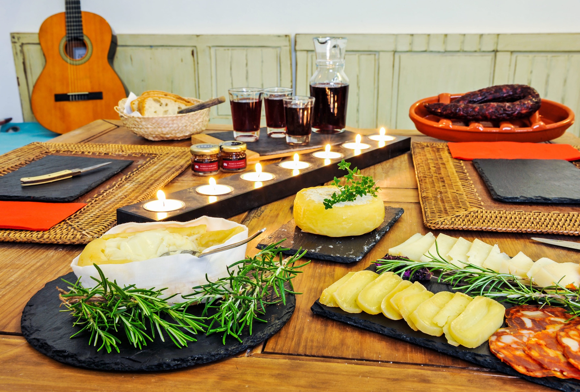Mesa de petiscos regionais com queijo amanteigado, enchidos e guitarra ao fundo