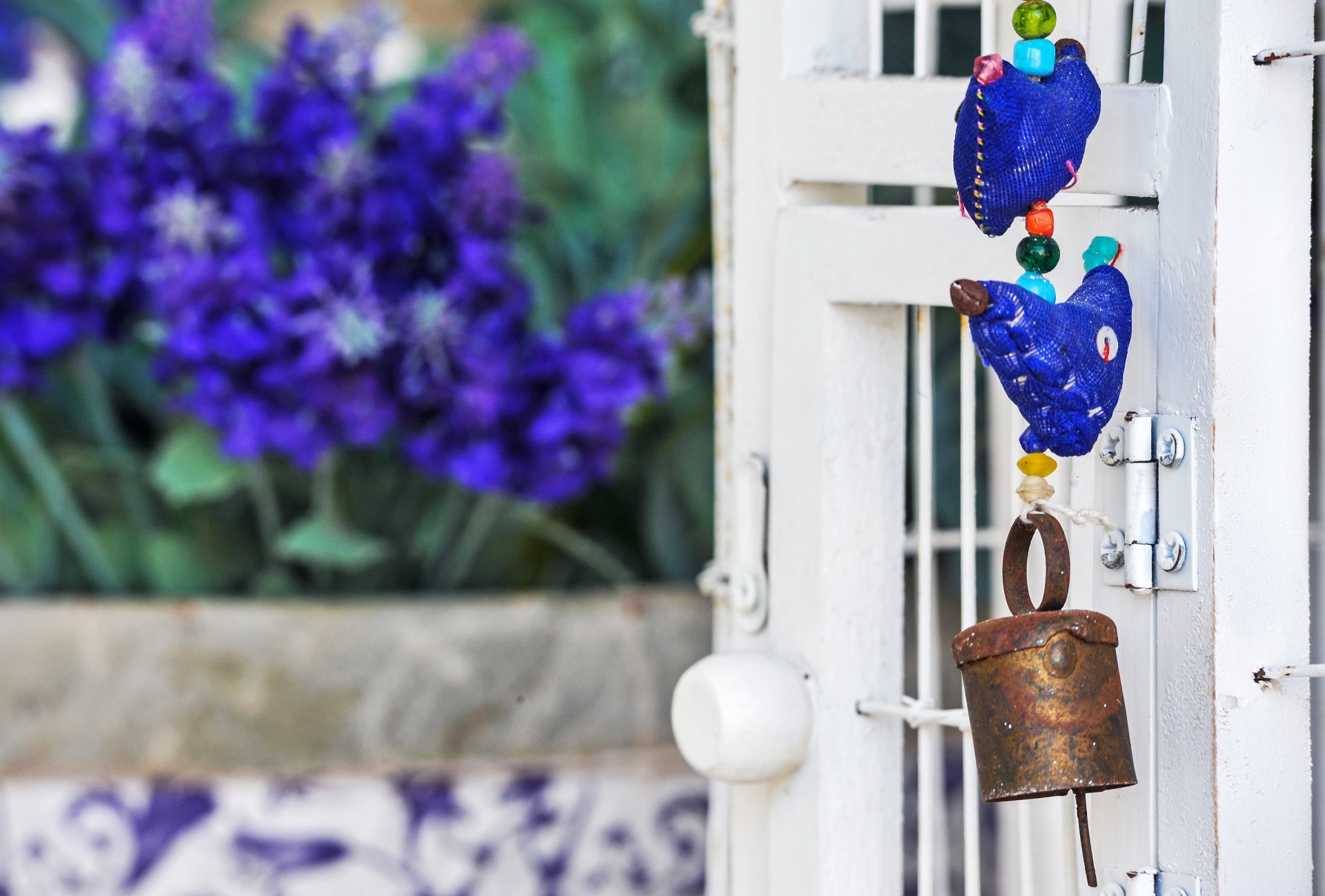 Pormenor decorativo: pendente artesanal azul junto a alfazema e azulejos portugueses