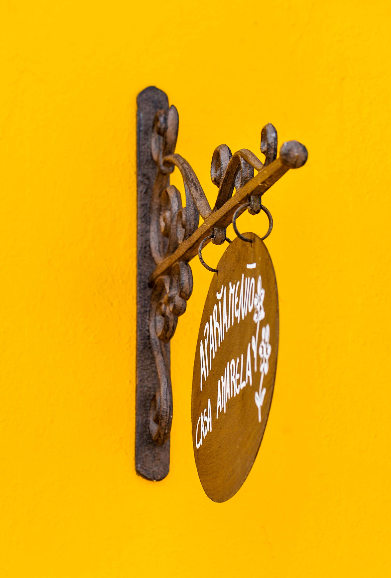 Placa em ferro forjado do Apartamento Casa Amarela sobre parede amarela