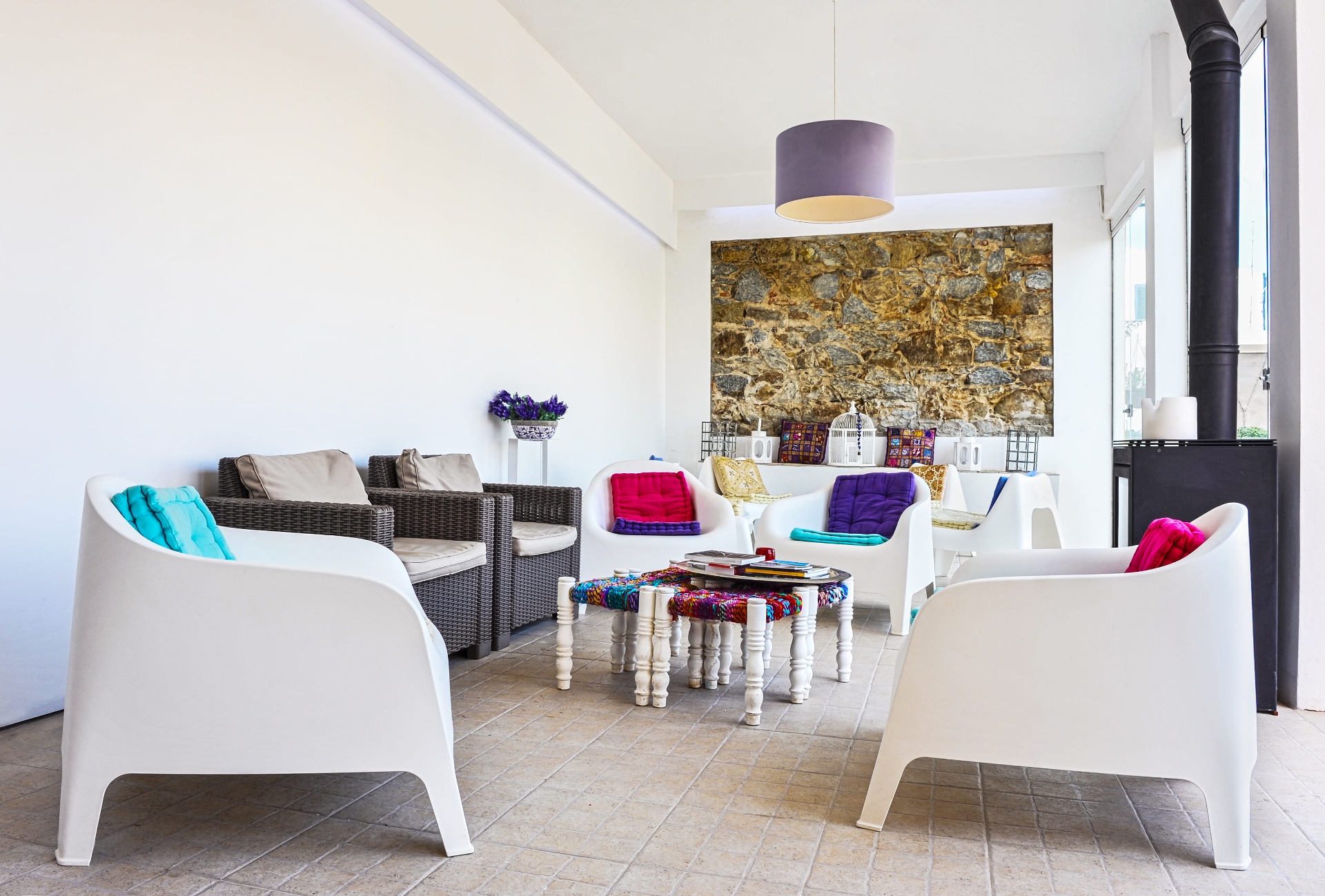 Lounge interior da Casa Amarela com poltronas brancas e almofadas coloridas