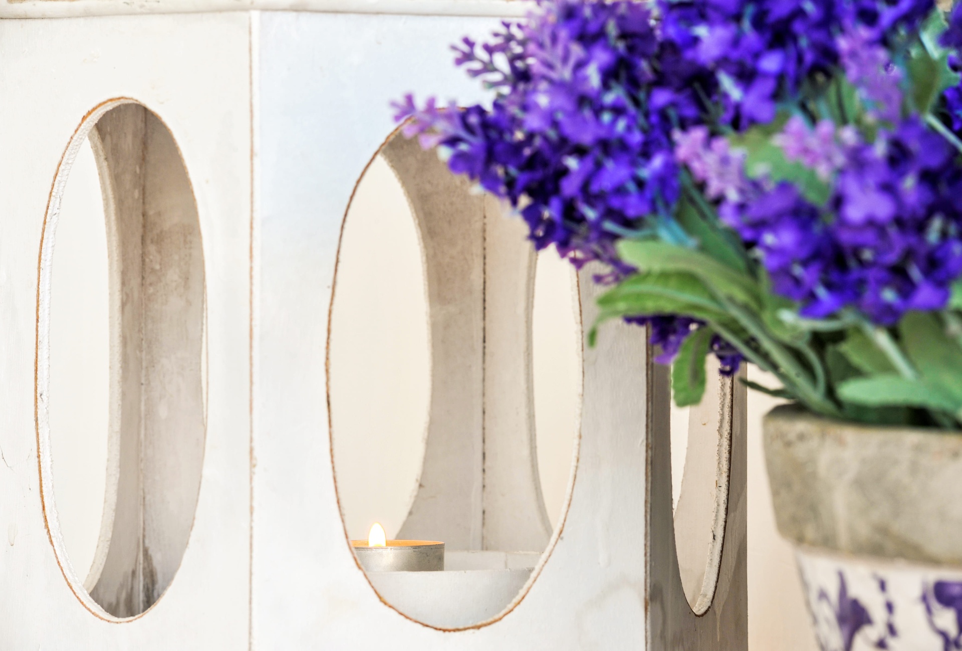 Pormenor decorativo com lanterna branca e arranjo floral roxo