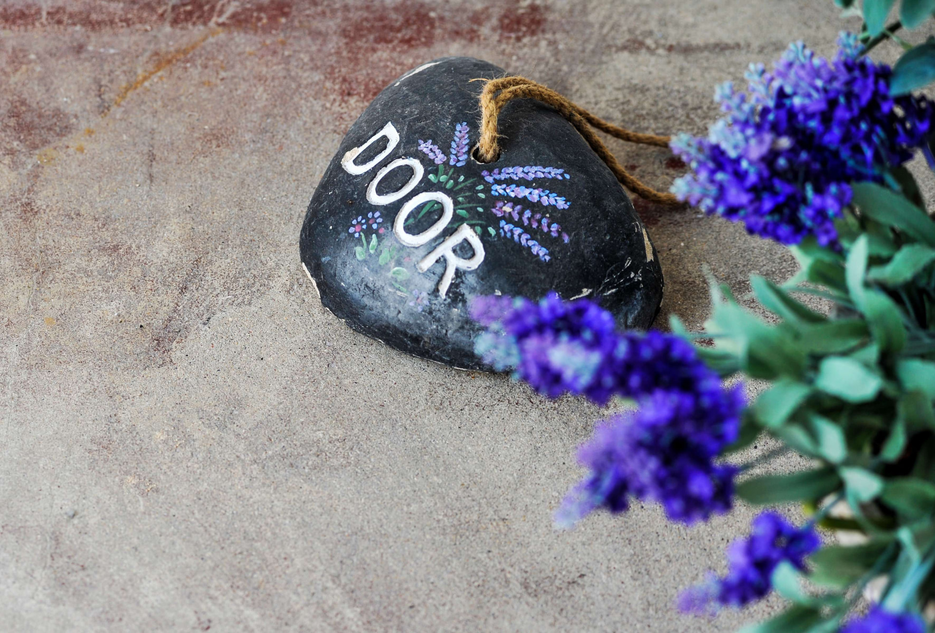 Seixo pintado à mão com a palavra DOOR e alfazema em flor